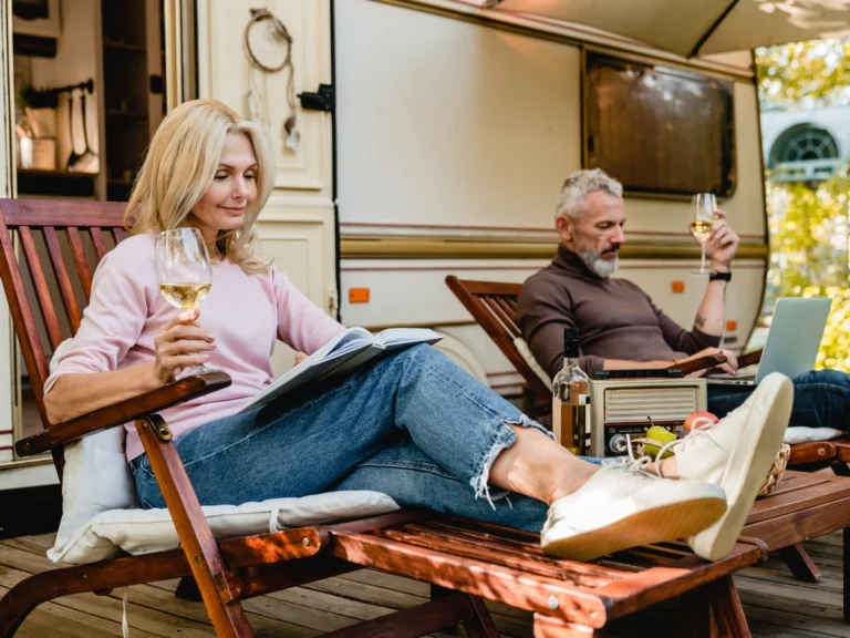 What Makes a Resort Stand Out - couple enjoying glasses of wine and reading near their RV